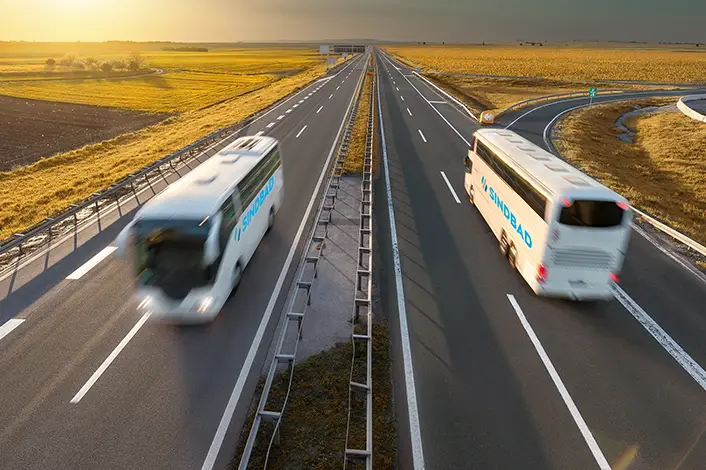 two Sindbad coaches passing each other on a highway symbolizing route optimization
